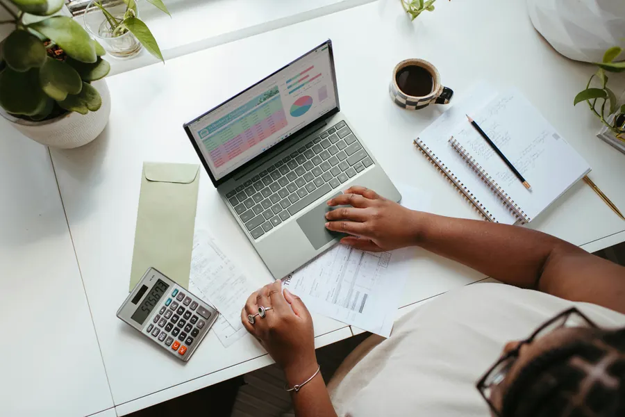 Un bureau avec une calculatrice, un ordinateur portable et des documents comptables